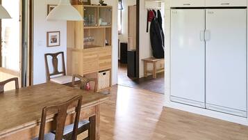 A dining area with a wooden table and chairs, a cabinet with glass doors, and a white wardrobe.
