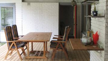 A wooden deck with a table and chairs, a brick wall, and a hanging light fixture.