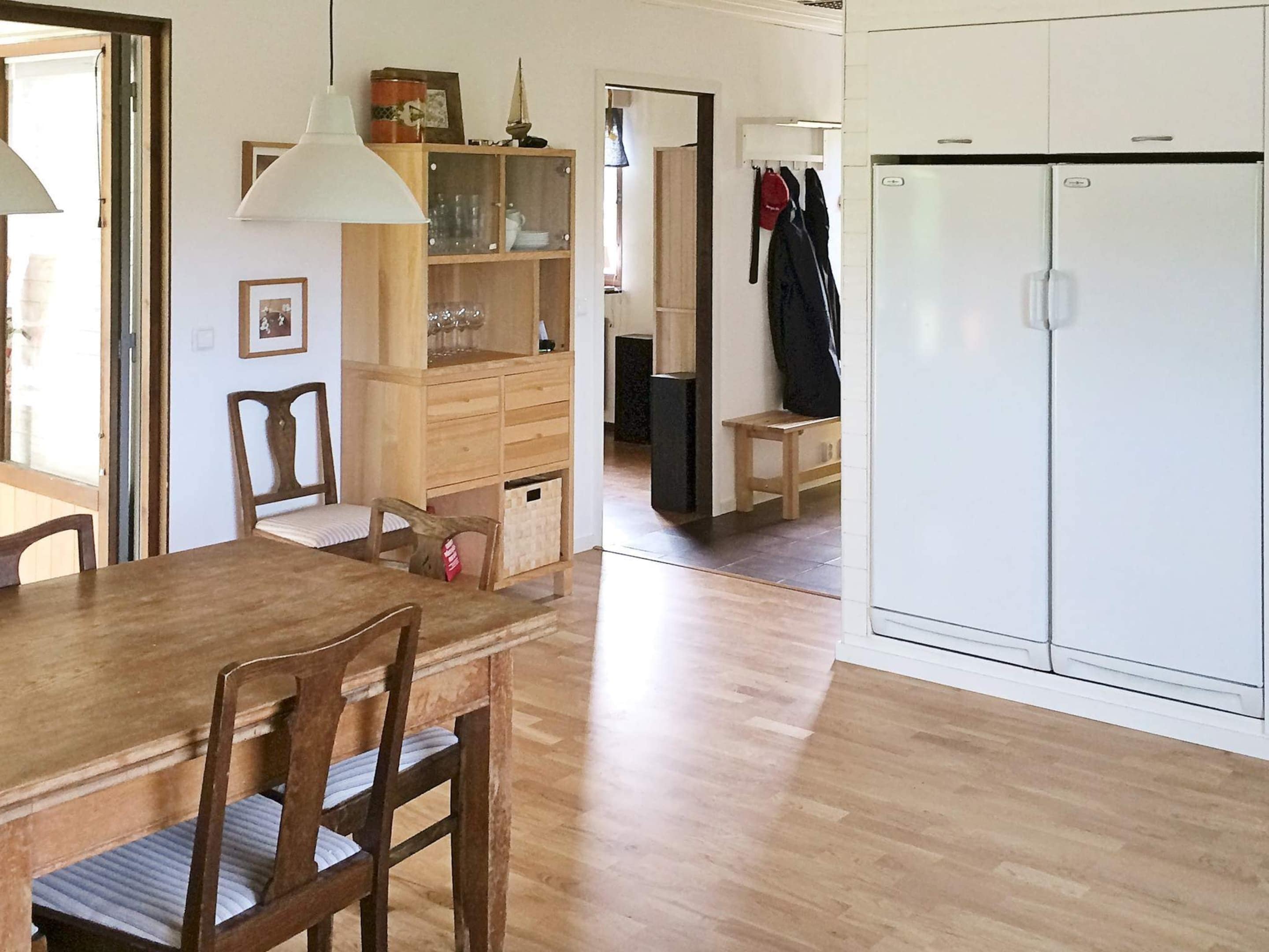 A dining area with a wooden table and chairs, a cabinet with glass doors, and a white wardrobe.