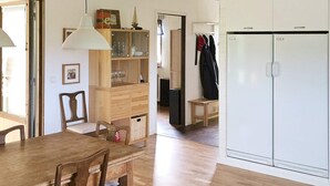 Un coin repas avec une table et des chaises en bois, un meuble avec des portes en verre et une armoire blanche.