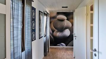 A hallway with a wooden floor, a door on the right, and a wall with a rock stack mural.