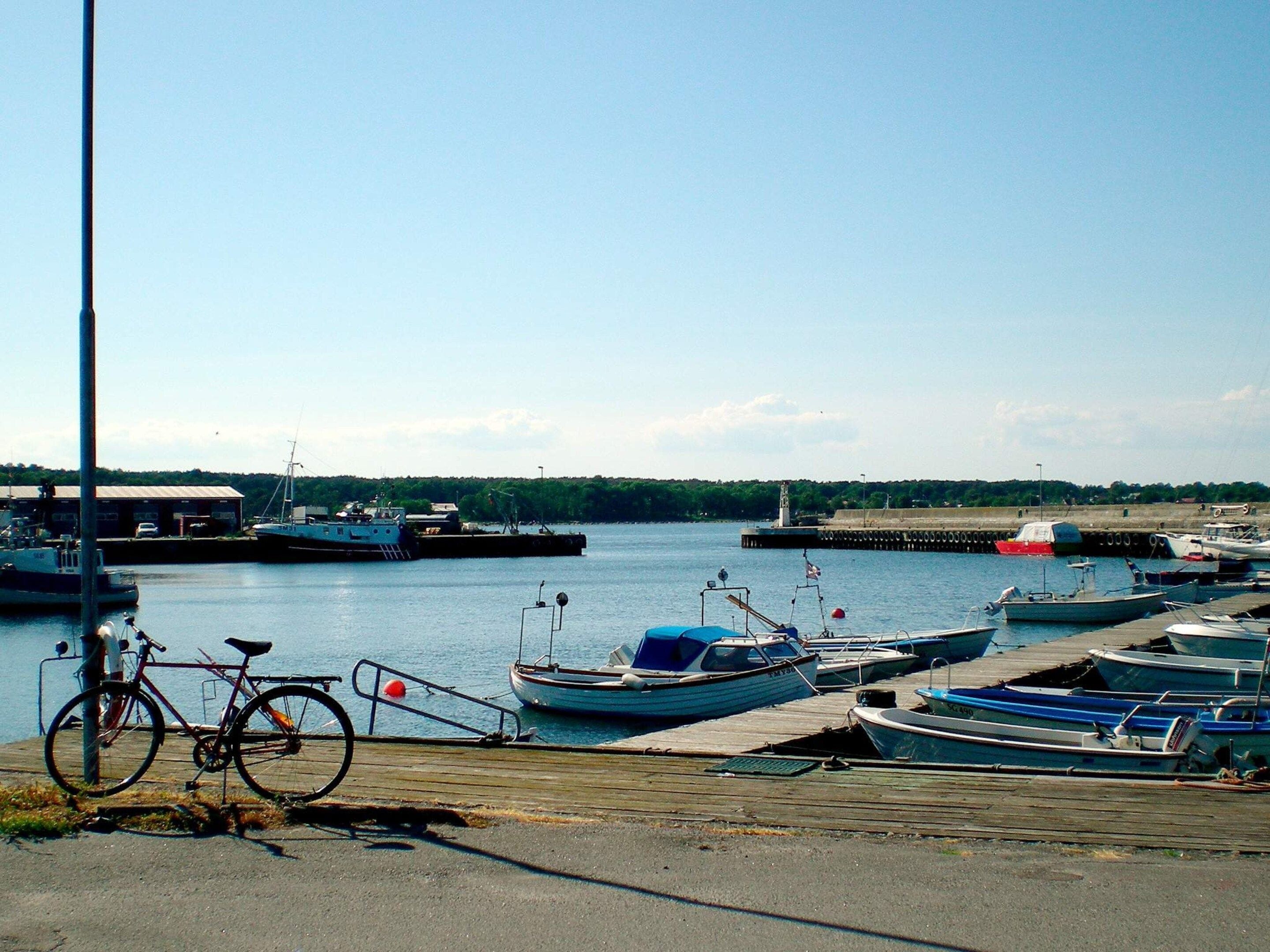 A marina with boats docked, a bicycle, and a clear sky.