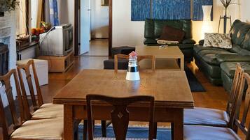 A cozy living room with a wooden dining table, chairs, a sofa, and a television.