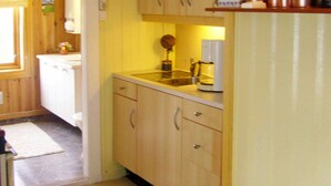 A compact kitchen with wooden cabinets, a sink, and a coffee maker. - 6 Person Holiday Home in Lyngdal (Lyngdal)