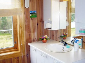 A bathroom with a wooden interior, a white sink, a mirror, and a window with a view of greenery. - 6 Person Holiday Home in Lyngdal (Lyngdal)