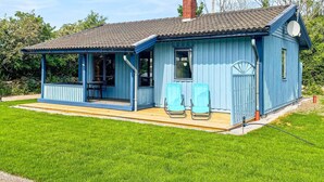 A blue wooden house with a porch, two chairs, and a chimney. - 4 Star Holiday Home in Kopingsvik (Kopingsvik)