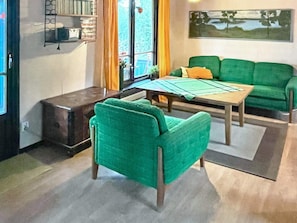 A living room with a green sofa, a wooden coffee table, and a small side table. - 4 Star Holiday Home in Kopingsvik (Kopingsvik)