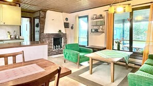 A cozy living room with a fireplace, a dining table, and a green sofa. - 4 Star Holiday Home in Kopingsvik (Kopingsvik)