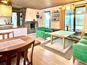 A cozy living room with a fireplace, a dining table, and a green sofa. - 4 Star Holiday Home in Kopingsvik (Kopingsvik)