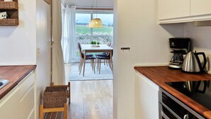 A modern kitchen with wooden countertops, a built-in oven, and a coffee maker. - 6 Person Holiday Home in Gudhjem (Gudhjem)