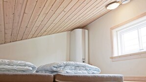 Une pièce avec un plafond en pente, une grande fenêtre et un lit avec un matelas et des oreillers.
