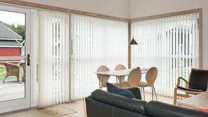 Un intérieur moderne comprenant un coin repas, un canapé et une porte-fenêtre coulissante donnant sur un espace extérieur.