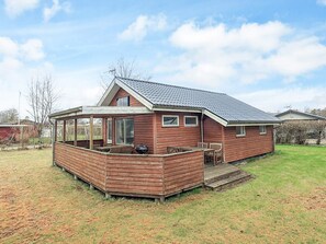 Une maison en bois dotée d’un patio couvert, d’un barbecue et d’une petite terrasse.