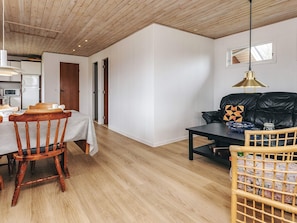 Un intérieur moderne comprenant un coin repas, un canapé en cuir noir et un plafond en bois.