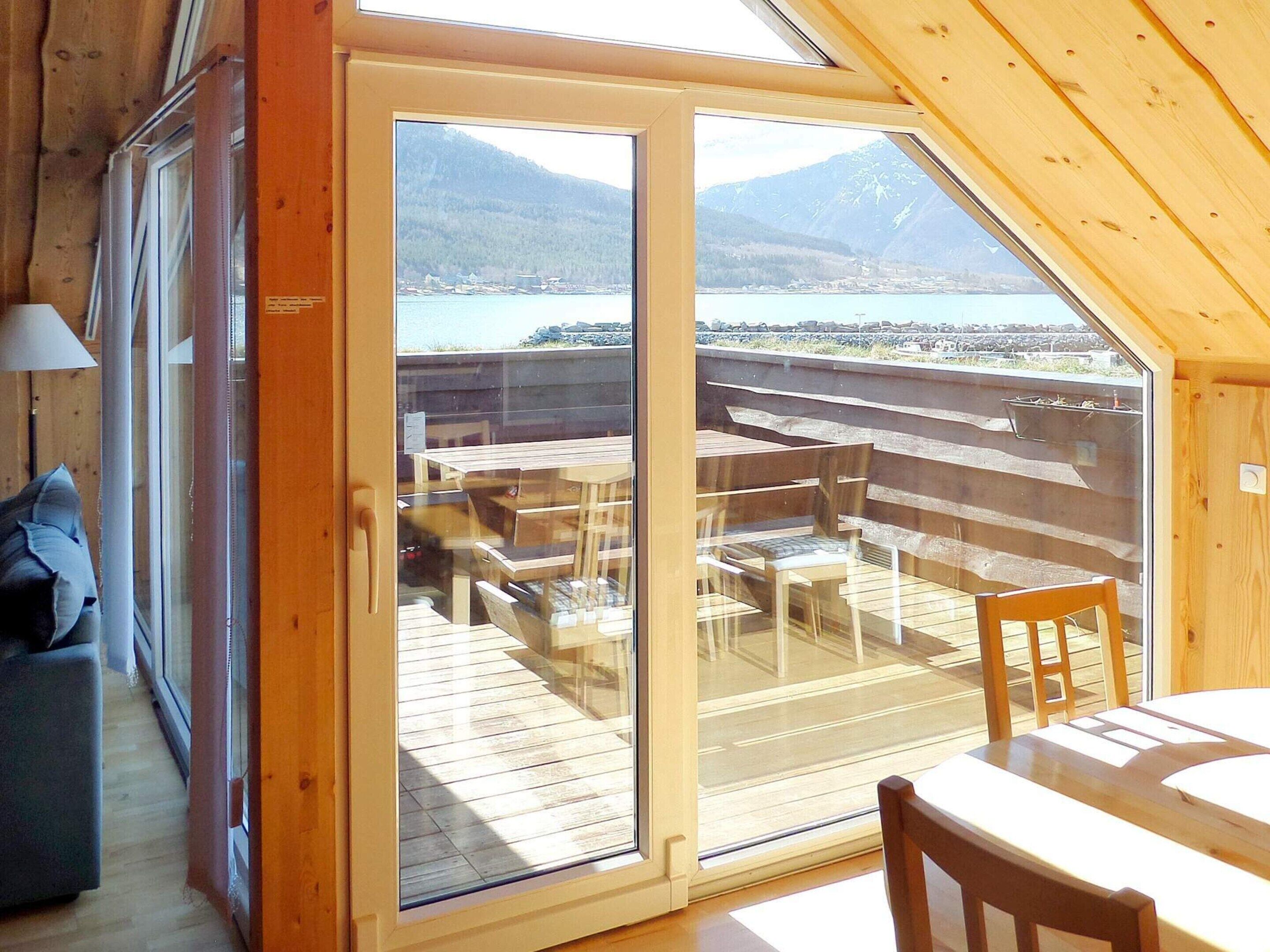 A wooden interior with a sliding glass door leading to an outdoor deck with wooden furniture.