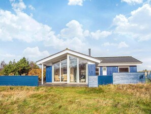 A modern house with a glass-enclosed porch, a separate garage, and a large lawn.