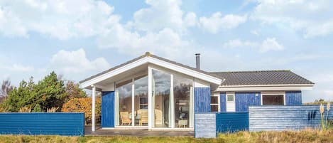 Une maison moderne dotée d’un porche entièrement vitré, d’un garage séparé et d’une grande pelouse.
