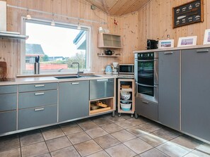 A modern kitchen with grey cabinets, a stainless steel oven, a microwave, and a sink. - 4 Star Holiday Home in Fano (Fano)