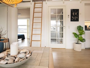 Experience a clean, minimalist space with a large window, wooden ladder, and potted plant.