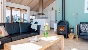 A modern living room with a black leather sofa, a wooden coffee table, and a fireplace. - 8 Person Holiday Home in Ulfborg-by Traum (Ulfborg)
