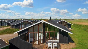 A modern vacation home with a large glass door entrance, a deck with outdoor seating, and a view of the surrounding landscape. - 8 Person Holiday Home in Ulfborg-by Traum (Ulfborg)
