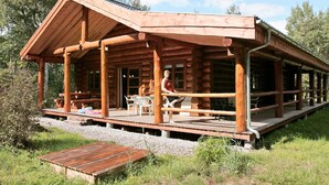 A wooden cabin with a covered porch and outdoor seating area. - 5 Star Holiday Home in Hadsund (Hadsund)