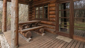 A log cabin with a wooden deck, a picnic table, and large windows. - 5 Star Holiday Home in Hadsund (Hadsund)
