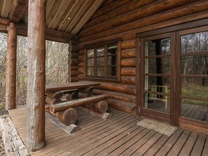 A log cabin with a wooden deck, a picnic table, and large windows. - 5 Star Holiday Home in Hadsund (Hadsund)