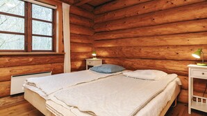 A wooden cabin bedroom with two beds, a window, a nightstand, and a lamp. - 5 Star Holiday Home in Hadsund (Hadsund)