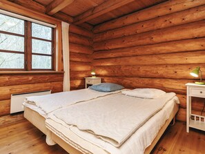 A wooden cabin bedroom with two beds, a window, a nightstand, and a lamp. - 5 Star Holiday Home in Hadsund (Hadsund)