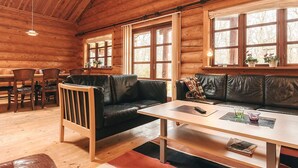 A log cabin interior with a wooden dining table, leather sofas, and large windows. - 5 Star Holiday Home in Hadsund (Hadsund)