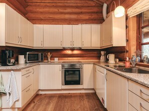 A kitchen with wooden cabinets, a microwave, a coffee maker, and a sink. - 5 Star Holiday Home in Hadsund (Hadsund)