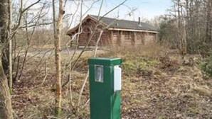 A wooden cabin with a green utility box in front. - 5 Star Holiday Home in Hadsund (Hadsund)