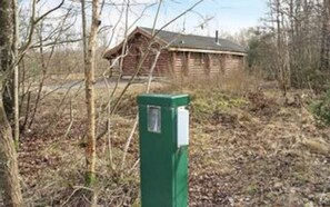 A wooden cabin with a green utility box in front.