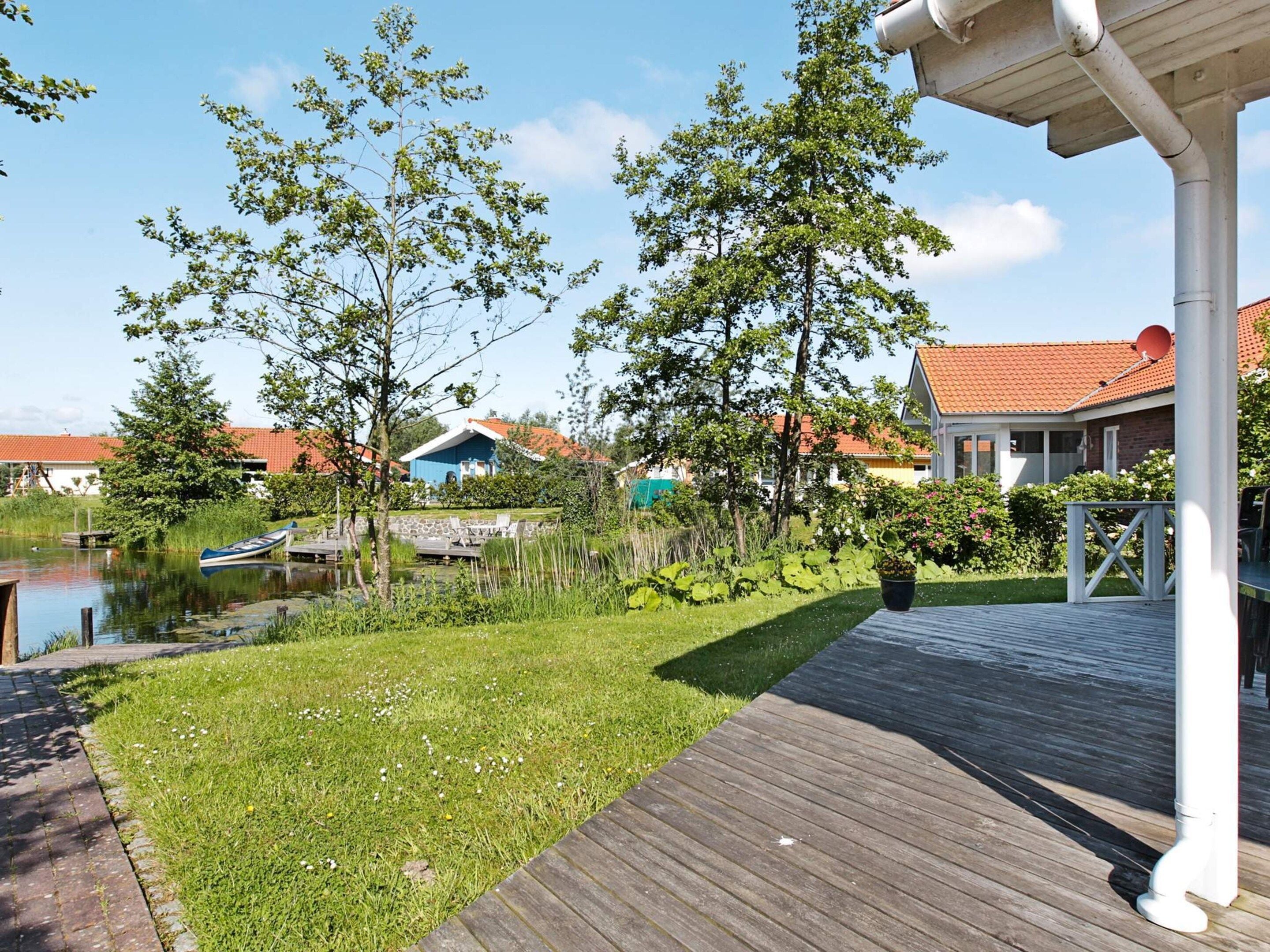A wooden deck with a view of a pond and surrounding greenery.
