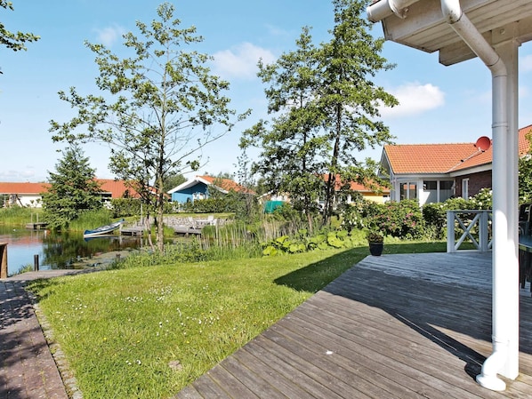 A wooden deck, a small pond, and a house with a red roof.