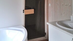 A bathroom with a white bathtub, a shower area, and a sink. - Holiday Home in Otterndorf (Otterndorf)