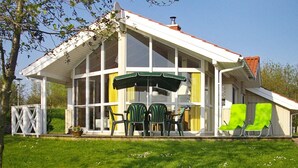 A house with a covered patio area, large windows, and outdoor seating. - Holiday Home in Otterndorf (Otterndorf)