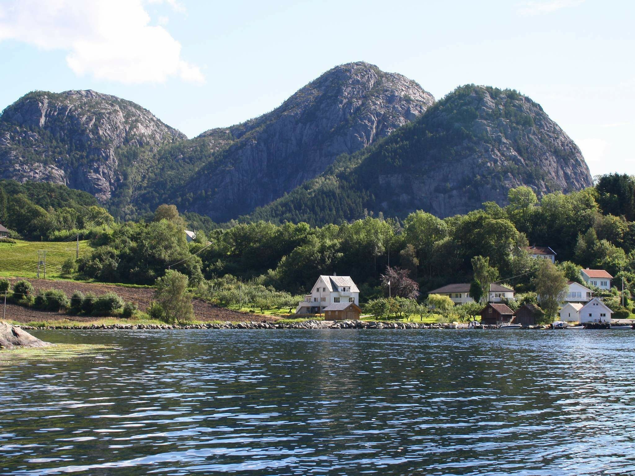 A lakeside village with houses near the water, surrounded by mountains.