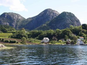 A lakeside village with houses near the water, surrounded by mountains.