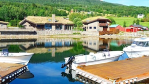 Une propriété au bord du lac, dotée d’un quai, de bateaux et d’une maison à la façade en pierre.