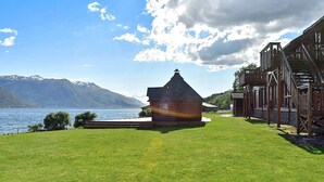 Un bâtiment en bois doté d’un toit à forte pente, d’un petit porche et offrant une vue sur un lac et des montagnes.