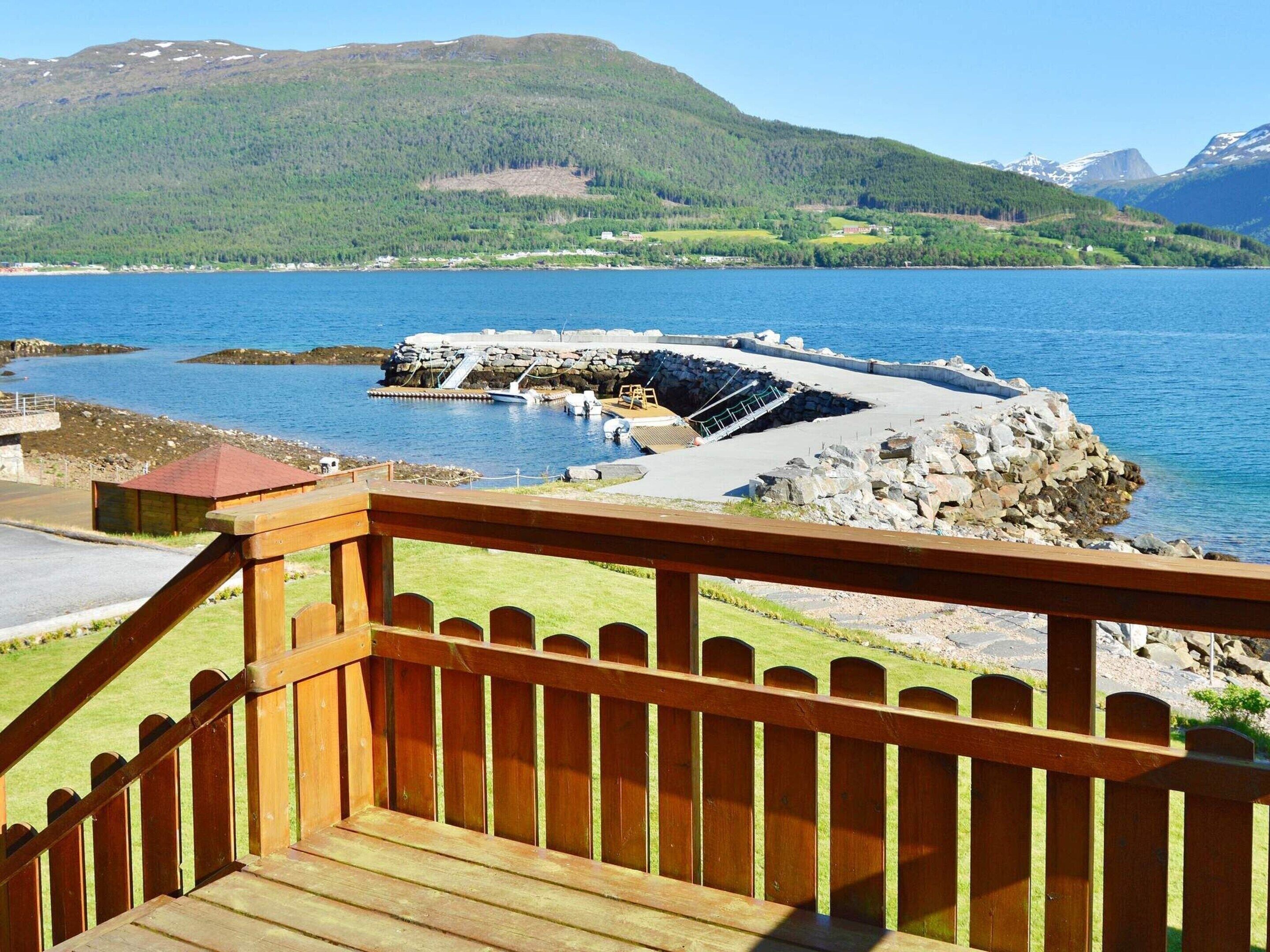 A wooden deck with a railing overlooking a body of water and a rocky shoreline.