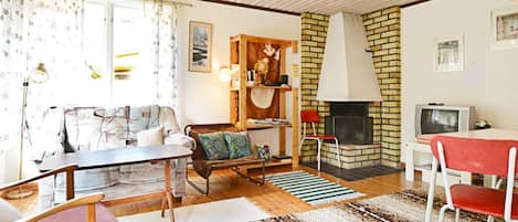 A cozy living room with a fireplace, a sofa, a dining table, and a television.