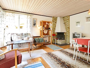 A cozy living room with a fireplace, a sofa, a dining table, and a television. - 4 Person Holiday Home in Monsteras (Monsteras)