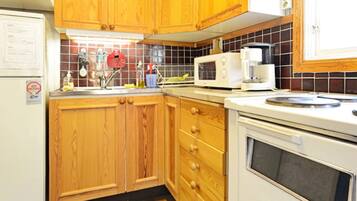 A kitchen with wooden cabinets, a microwave, a coffee maker, and a tiled backsplash.