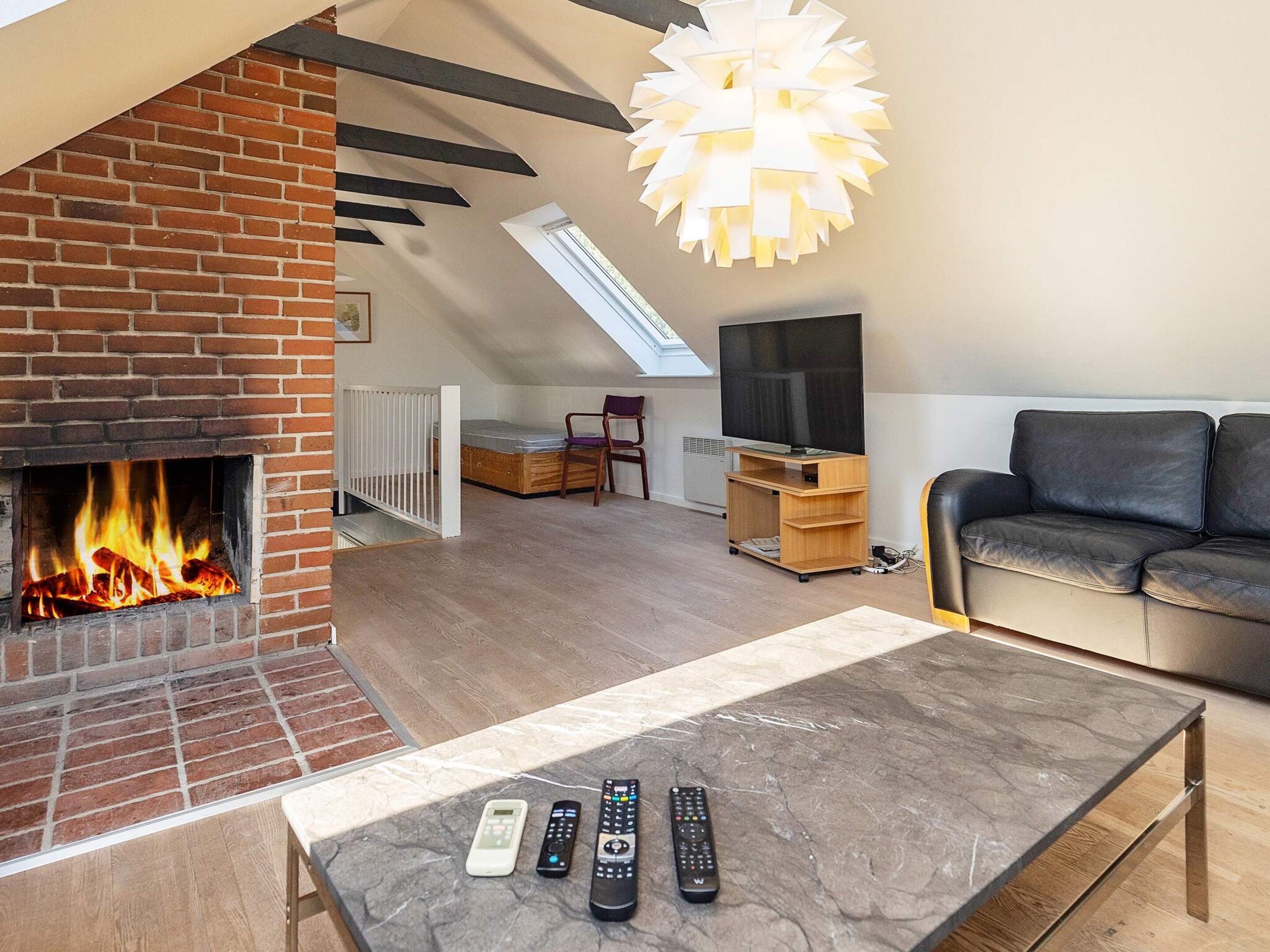 A living room with a fireplace, a sofa, a coffee table with remotes, and a TV stand.