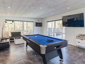 A modern living room with a pool table, a sofa, and a television.