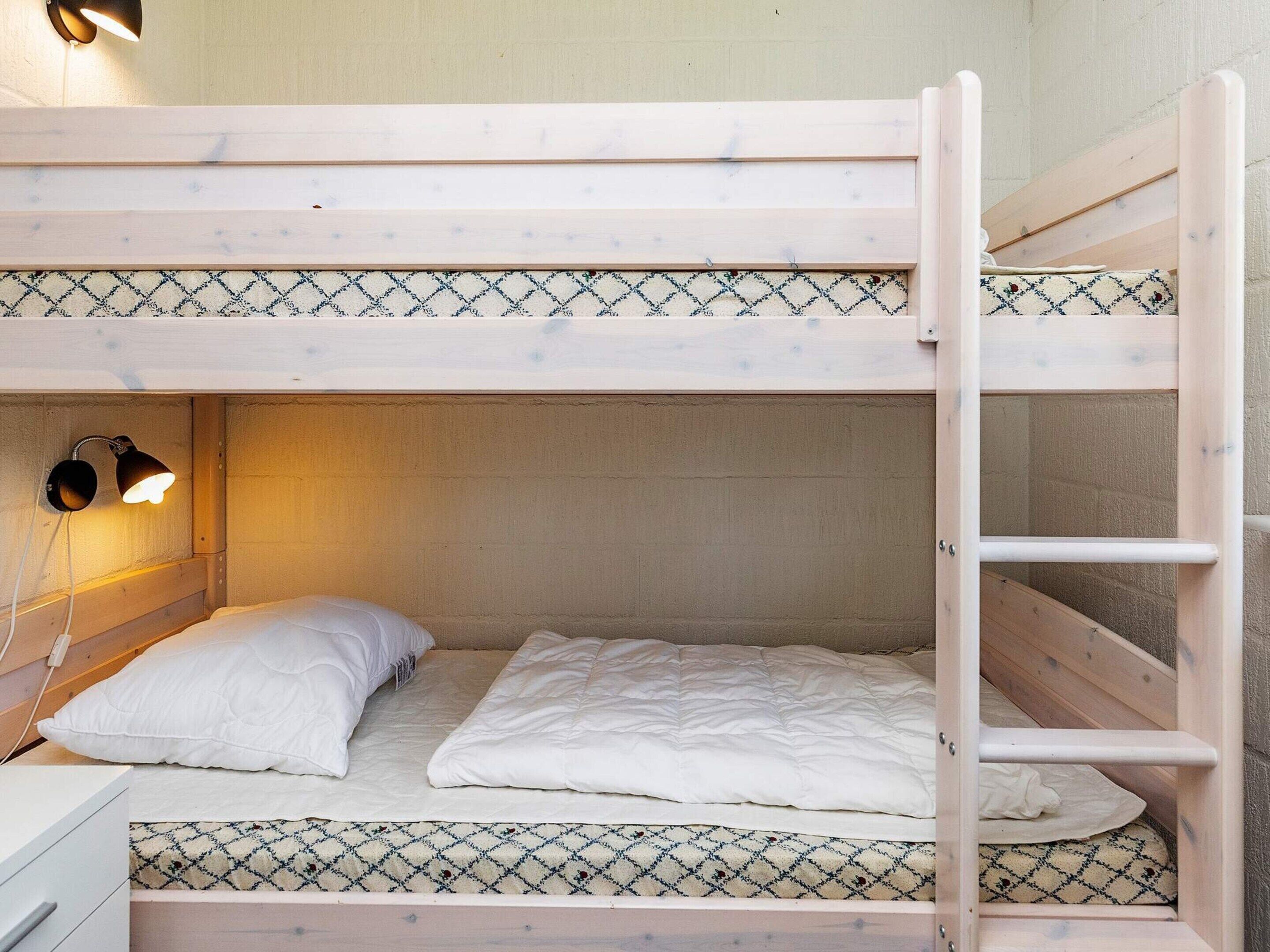 A bunk bed with a headboard, a bedside lamp, and a patterned bedspread.