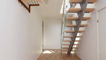 A modern interior with a wooden floor, a staircase with metal railings, and a light fixture.